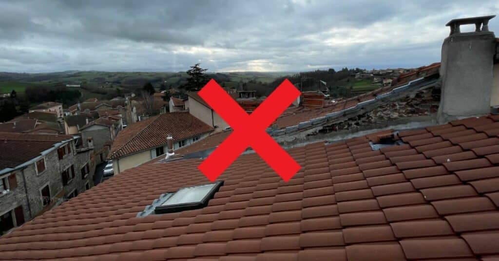 Photo d'un toit avec une croix rouge pour montrer pourquoi les ramoneurs ne montent plus sur les toits